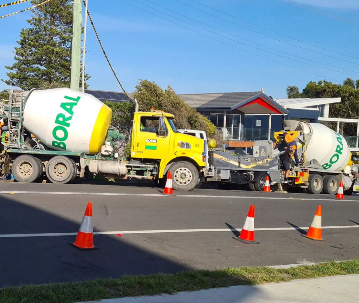 Concrete trucks lined up behind a row of Crown cones