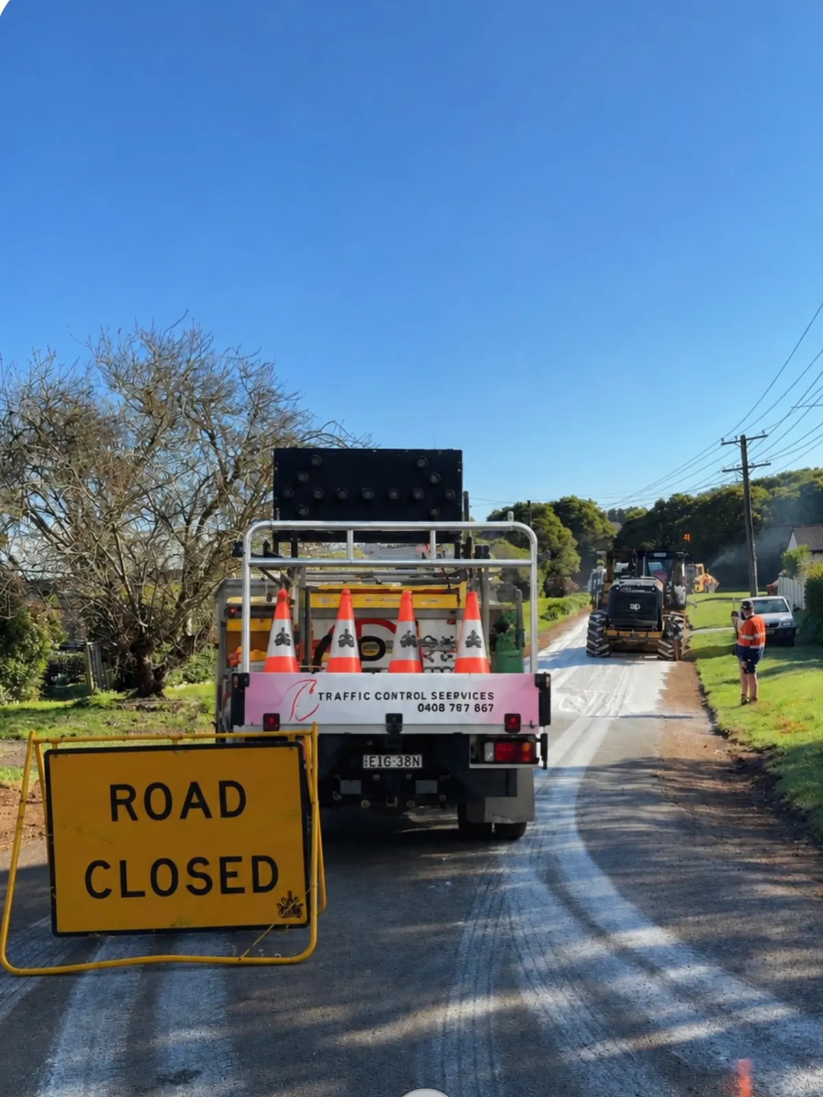 A Crown ute with an arrow board and a road closed sign on a country road